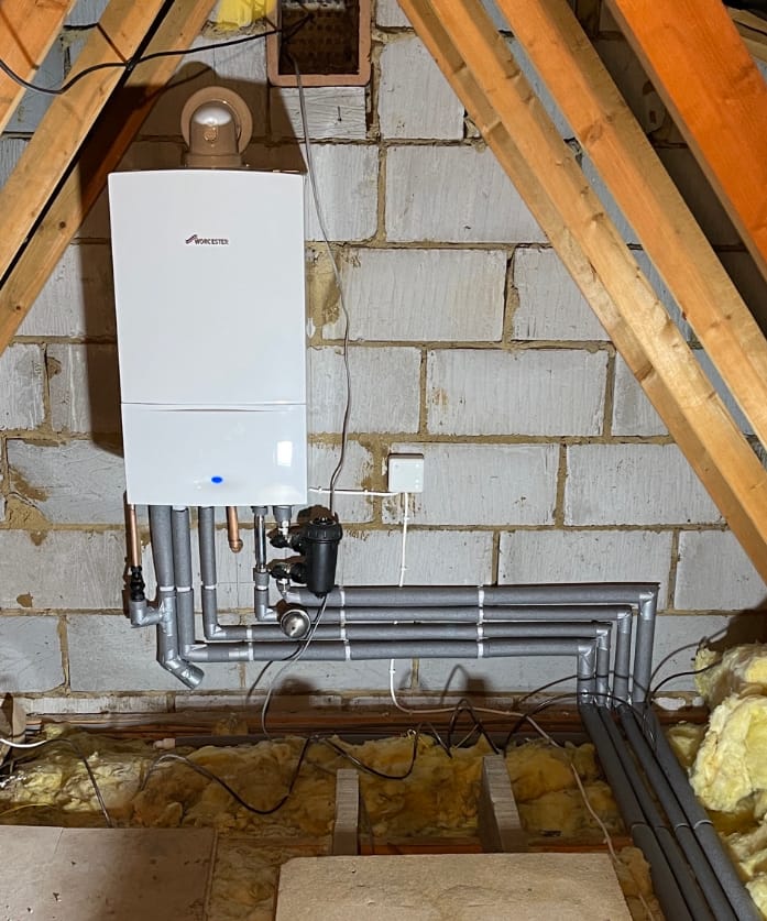 Wall-mounted boiler installation showing professional copper pipework
