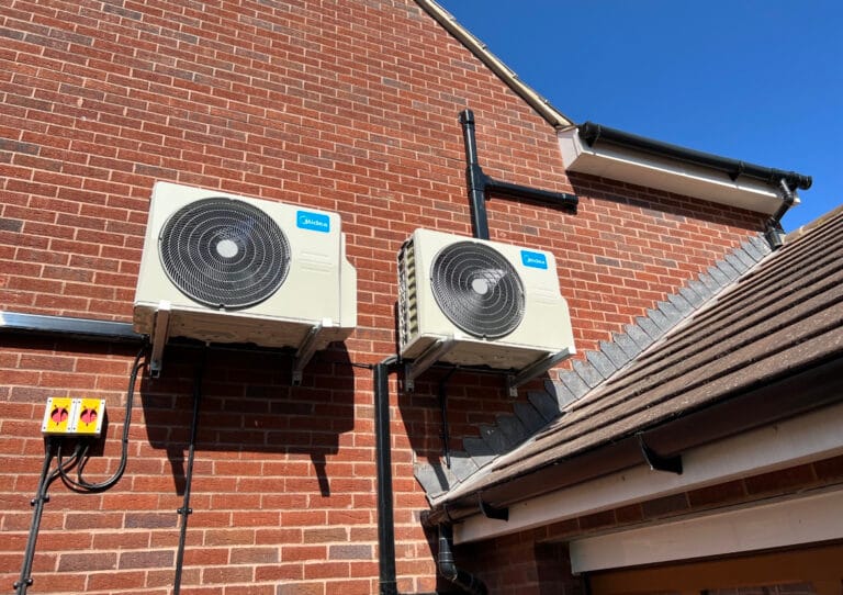 Dual Midea outdoor air conditioning installation on a brick property