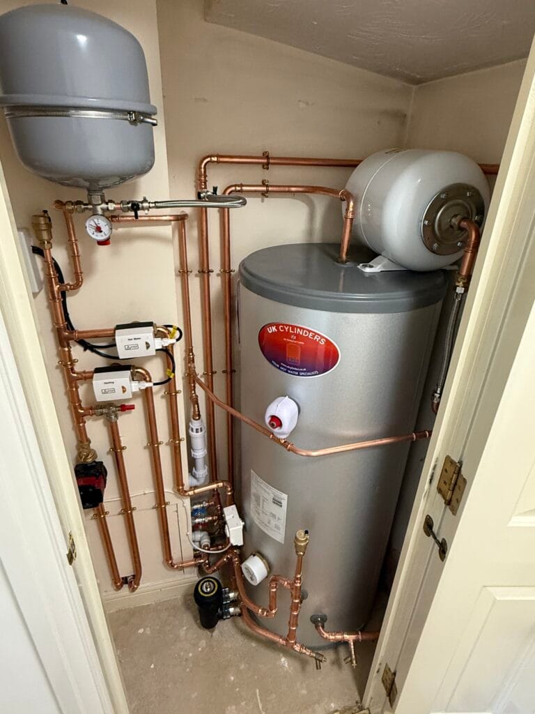 Unvented hot water cylinder installed in a cupboard with copper pipework and controls