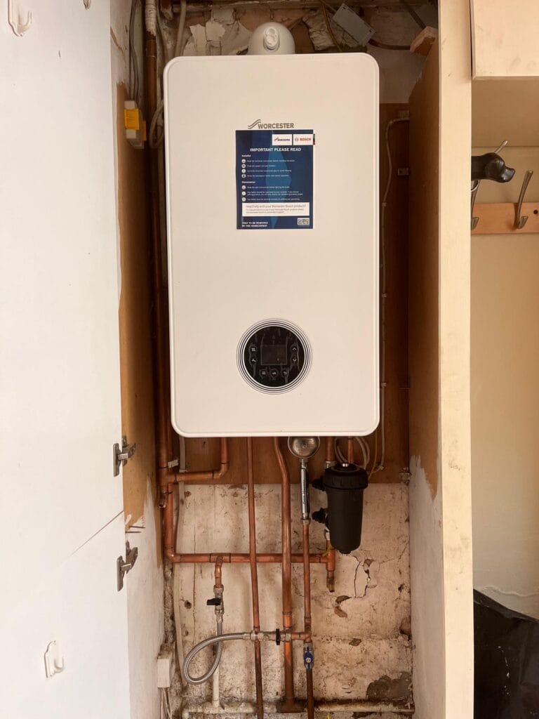 Wall-hung gas boiler installed above neatly arranged copper heating pipework